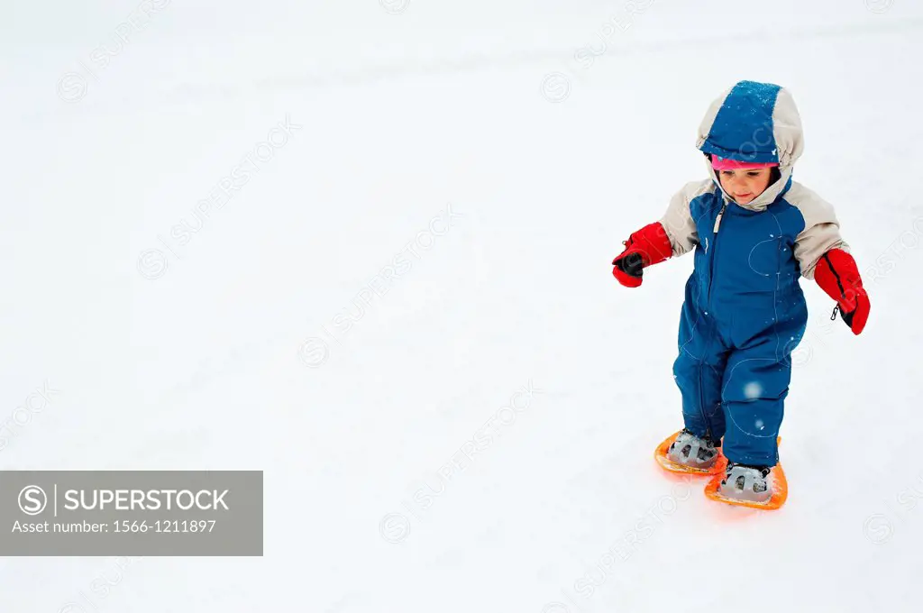 A two years old baby girl using snowshoes for her first time