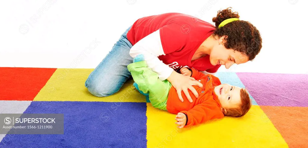 Mother Play with her ten months old baby girl on a colored carpet
