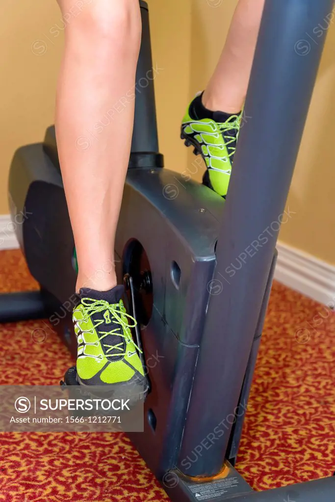Legs of female, 45, Caucasian, working out on cycling exercise machine, Texas, USA