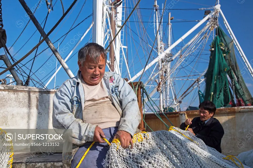 Biloxi, Mississippi - Shrimp fishermen work on their nets while docked on Biloxi´s Back Bay