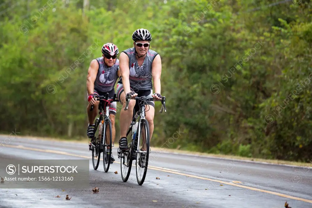 Crown Point, Louisiana - Bicycle riders in the rain on a road in Barataria Preserve, a part of Jean Lafitte National Historical Park and Preserve  Bar...