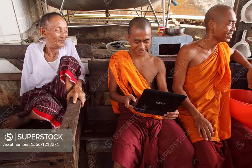 Three monks sitting having a chat and watching movie, , Myanmar, Burma, Asia