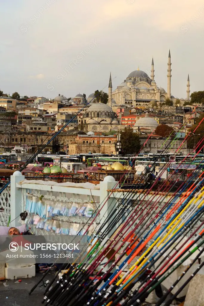 Man sleeping on Galata Bridge with fishing rods over Golden Horn with Suleymaniye Mosque Istanbul