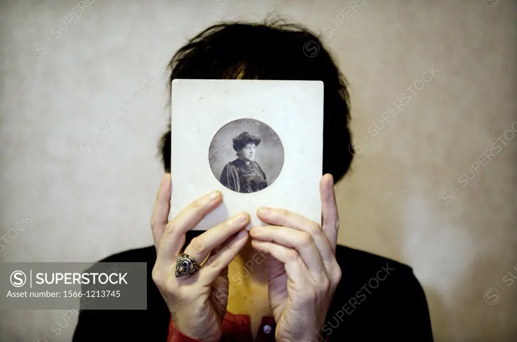 Mujer joven con retrato antiguo en las manos tapandole la cara, Young woman with old picture in her hands covering her face,