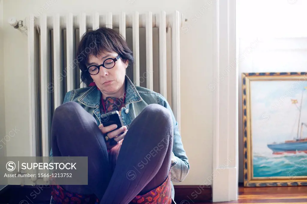 Mujer joven sentada en el suelo llamando por telefono, Young woman sitting on the floor calling by phone 
