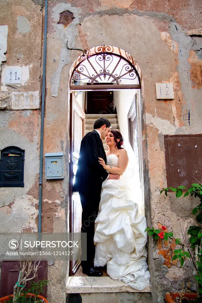 Wedding couple kissing on a doorstep. Rome, Italy.