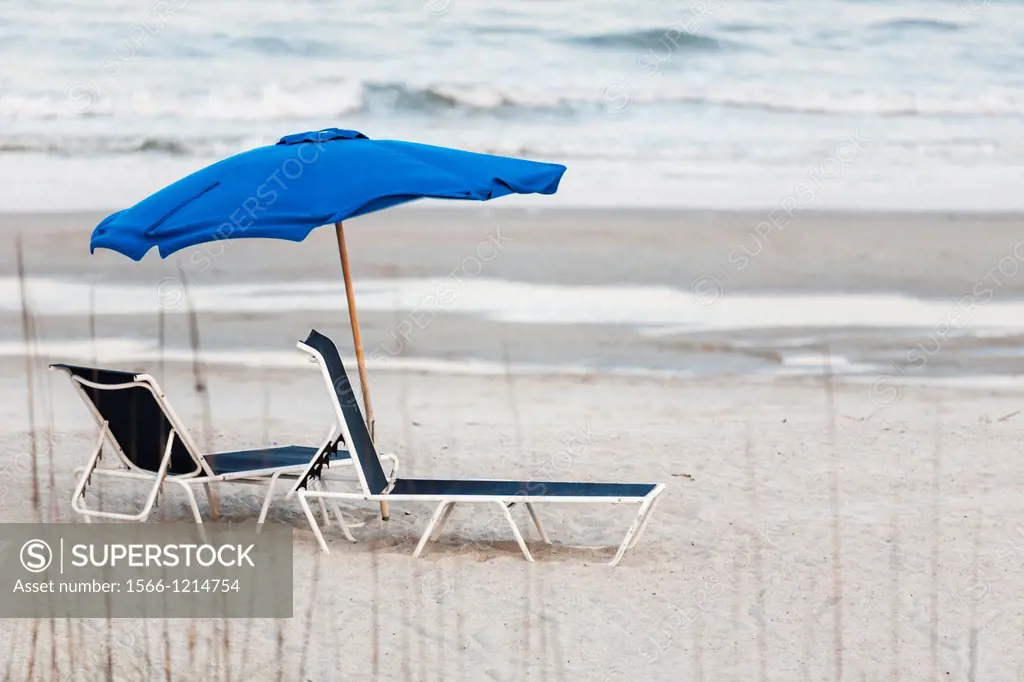 Empty beach lounge chairs under beach umbrella at Amelia Island, Florida