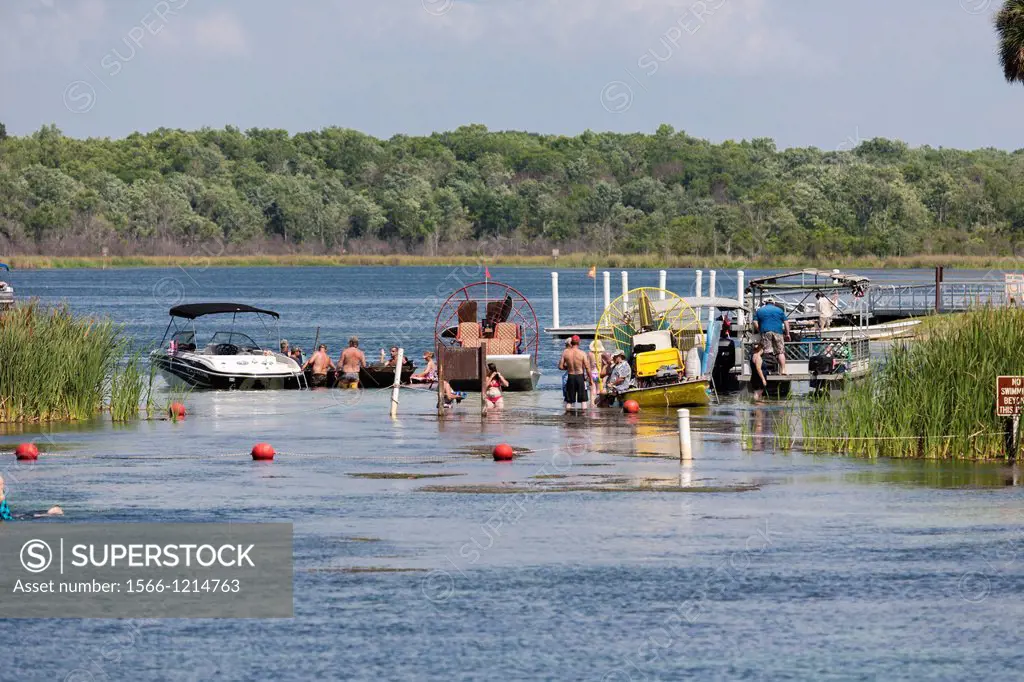 Young men and women boaters socialize on sandbar at Salt Springs Recreation Area in the Ocala National Forest, Florida