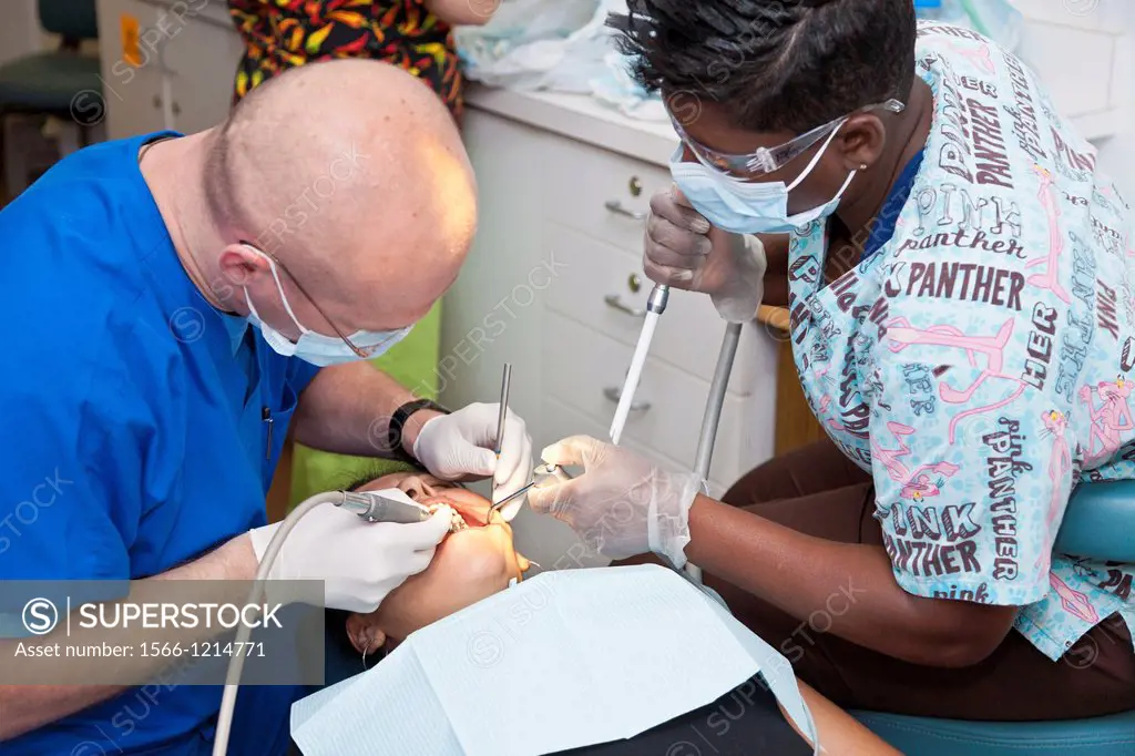 White male volunteer dentist and assistant provide dental services for black woman through Mission Smiles mobile dental clinic in Tampa, FL