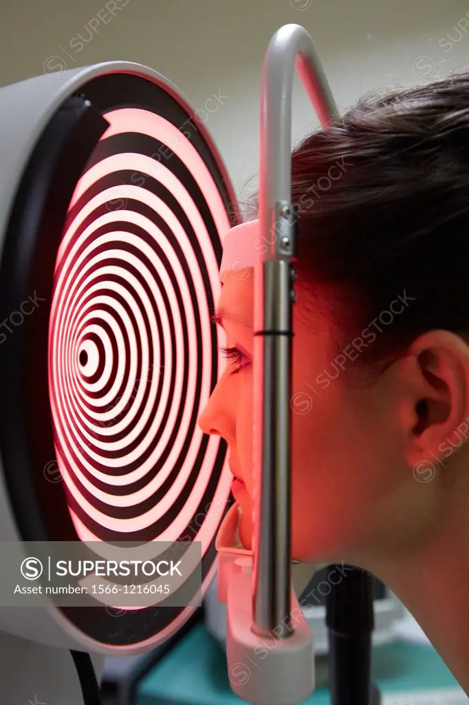Eye examination  Patient having a corneal topography measurement made of her eye  The device at centre projects bright rings onto the eye, which are r...