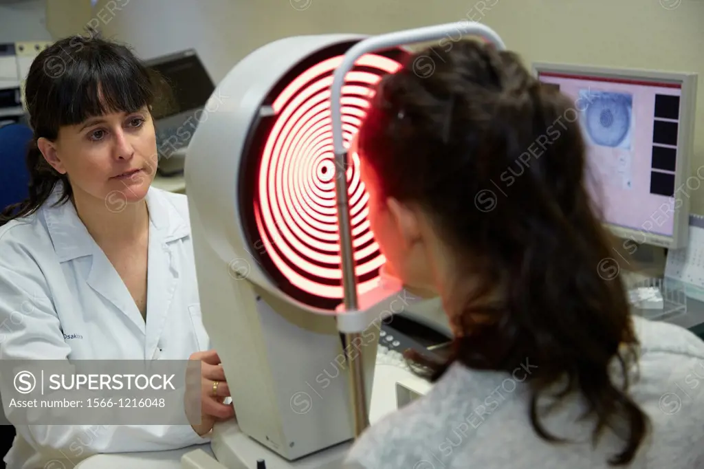 Eye examination  Patient having a corneal topography measurement made of her eye  The device at centre projects bright rings onto the eye, which are r...