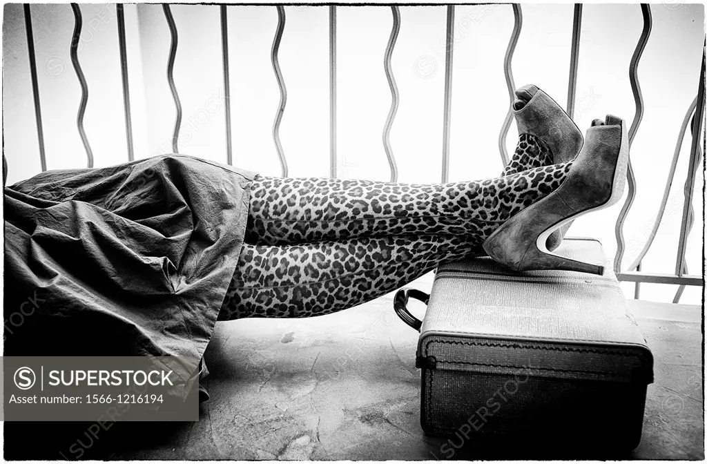 primer plano de piernas de mujer tumbada con zapatos de tacon y maleta, close up of woman legs lying with heel shoes and suitcase,
