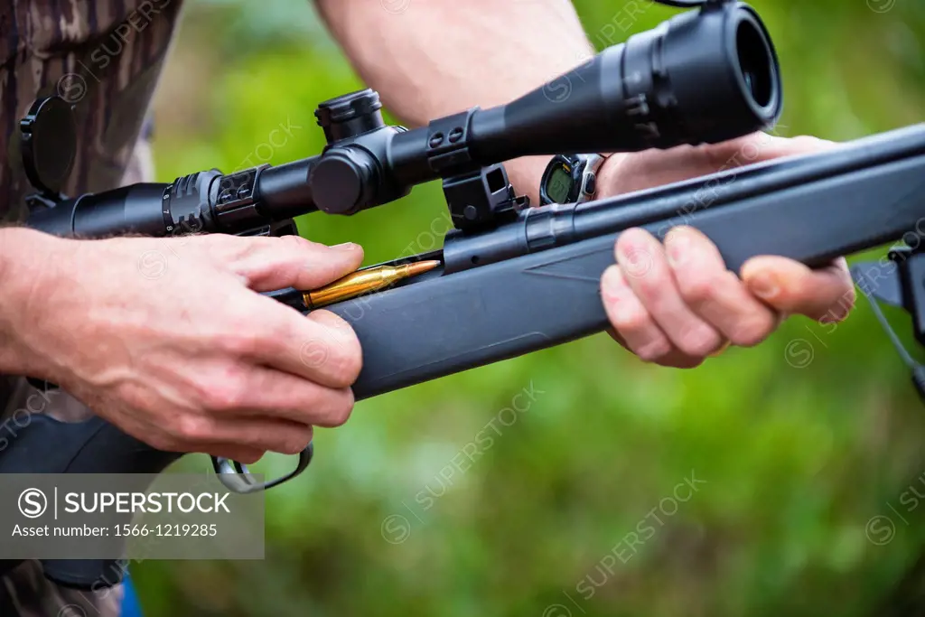 Close up of loading a hunting rifle firearm gun with ammunition bullets