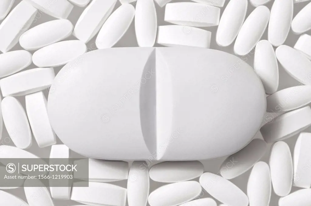 Generic White Lozenge Shaped Pills on a White Background with one large pell in the centre