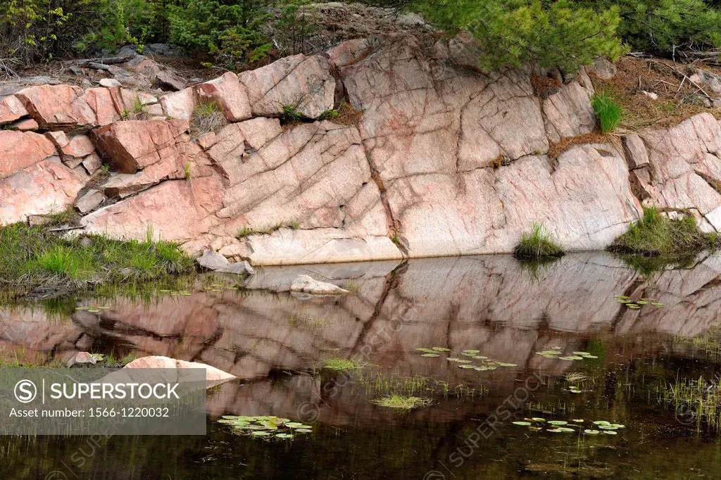 Canadian Shield granite outcrops reflected in a beaver pond, Killarney, Ontario, Canada