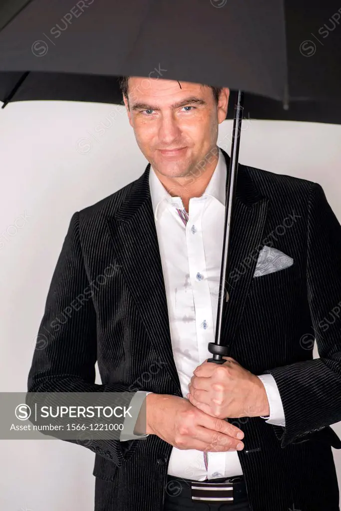 Handsome man in suit with wet face holds black umbrella