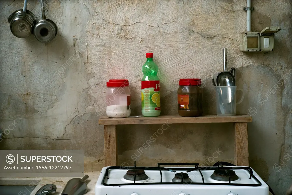 Closeup of a very simple and basic kitchen with utensils and several different botlles and pots.