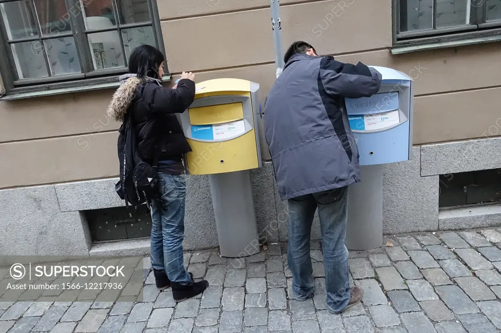 Asian tourists writing postcards on mailboxes, Stockholm, Sweden