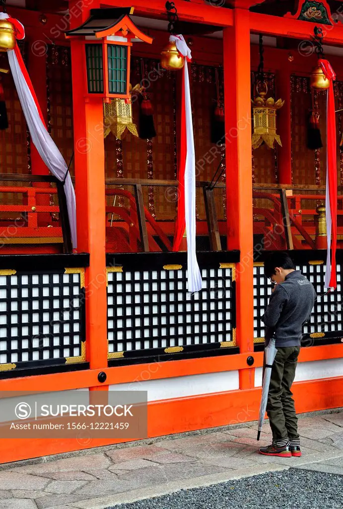 Young Japanese boy praying at Fushimi Inari-taisha Shrine, head shrine of Inari located in Fushimi-ku, Kyoto, Kansai Region, Japan.