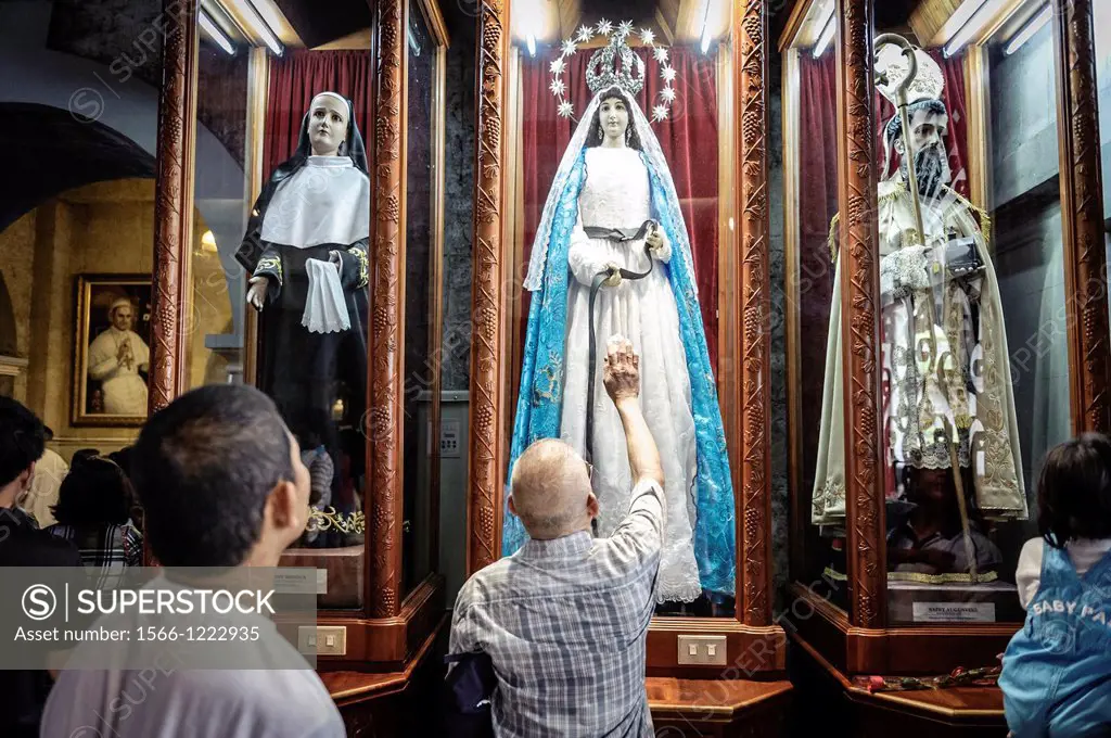 People praying in front of an statue of The Virgin Mary inside The Basilica Minore del Santo Niño, Cebu, Philippines
