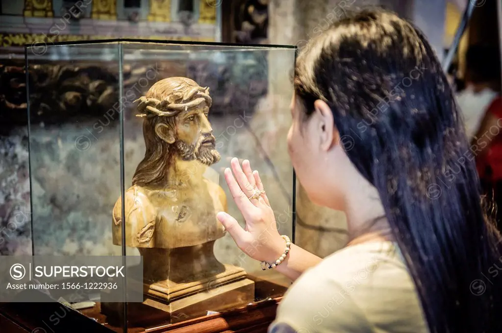 Woman praying in front of an statue of Christ inside The Basilica Minore del Santo Niño, Cebu, Philippines