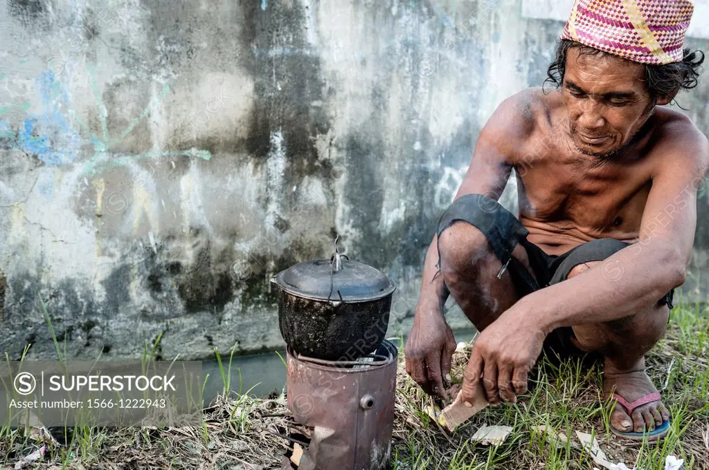 Homeless man cooking in the streets of Cebu, Visayas, Philippines, South East Asia