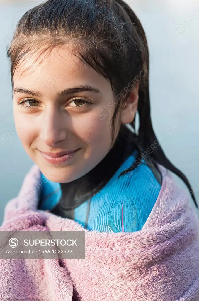 Girl aged 12 in a wetsuit and wrapped in a towel after a swim