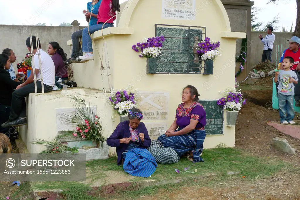 The cemetery is the heart of the Day of the Dead in Santiago Sacatepequez celebration with many families and widows sitting beside the graves of their...