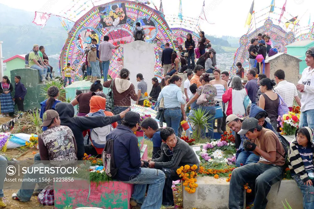 The cemetery is the heart of the Day of the Dead in Santiago Sacatepequez celebration with many families and widows sitting beside the graves of their...