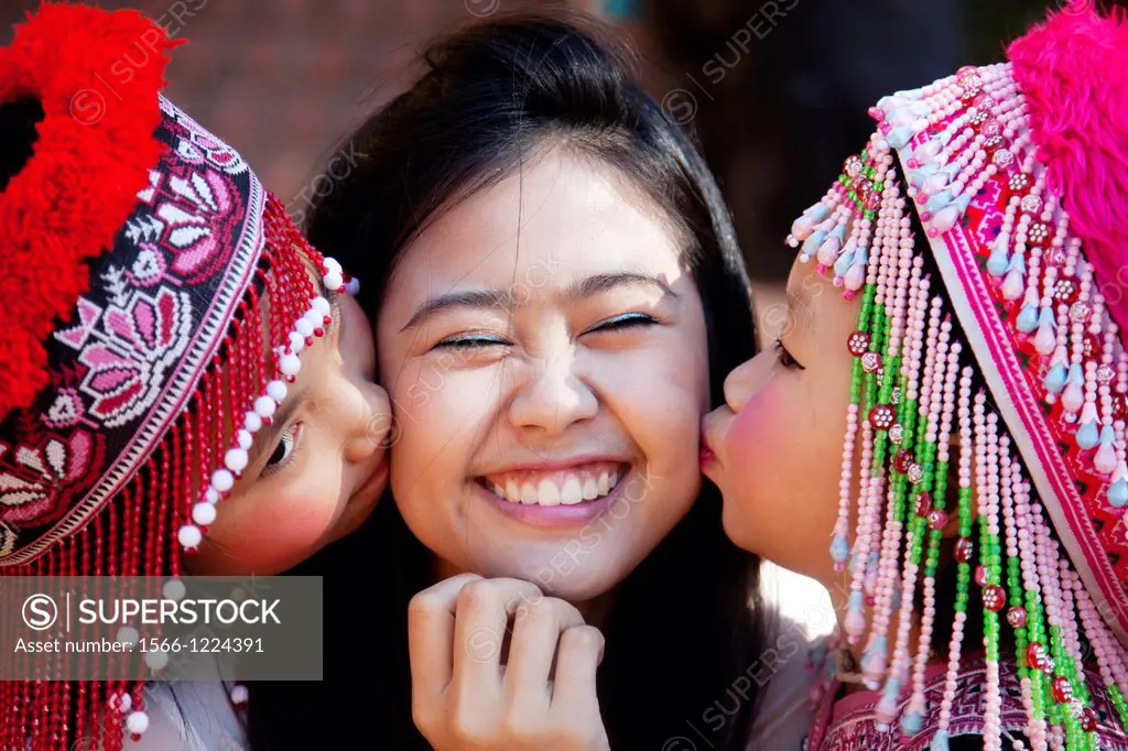 Two cute Meo Thai girls kissing an Asian tourist in Doi Suthep temple in Thailand