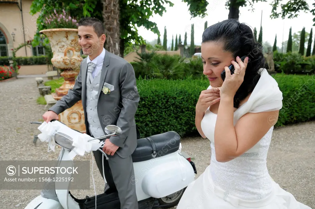 Italian wedding couple with a motor scooter Vespa in a garden park, Firenze, Tuscany, Italy
