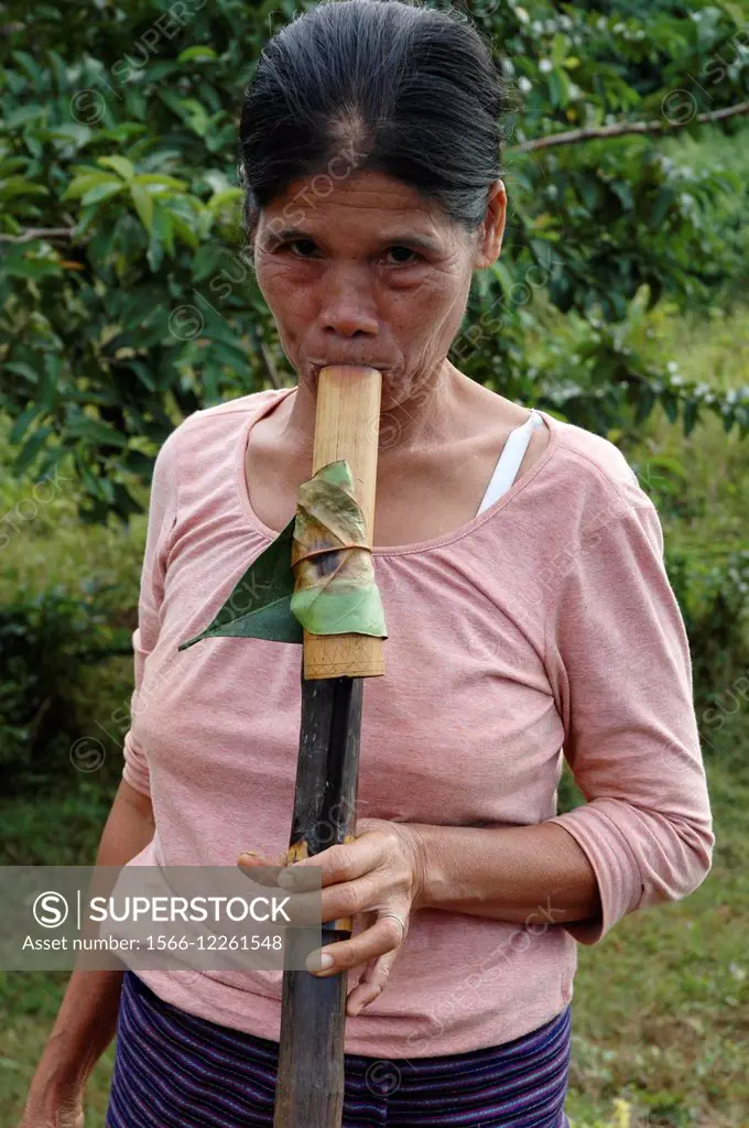 Laos: a woman smoking tobacco using a traditional pipe