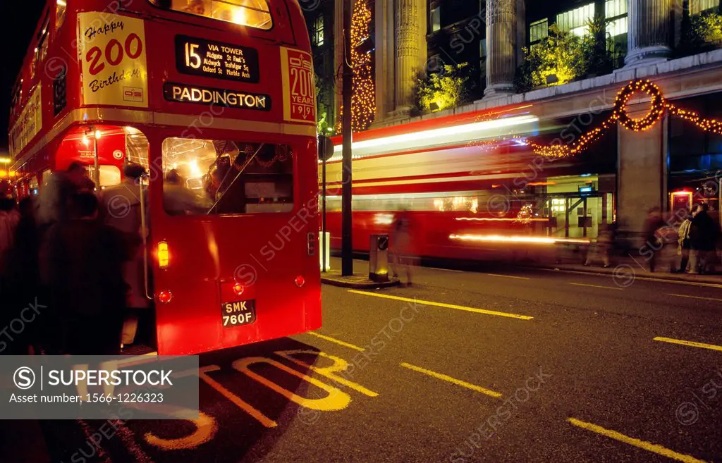 Red double-decker bus at a stop on Oxford Street at night, London, England, UK