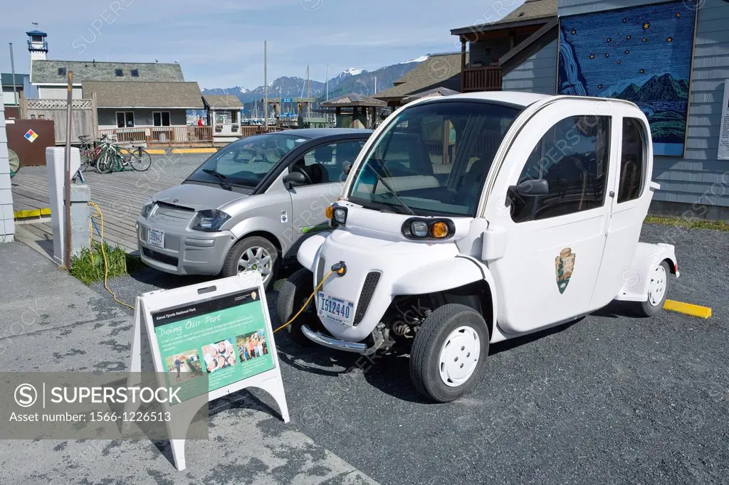 Small electric cars being charged outside Kenai Fjords National Park office and visitor center at small boat harbor, Seward, Alaska, late August