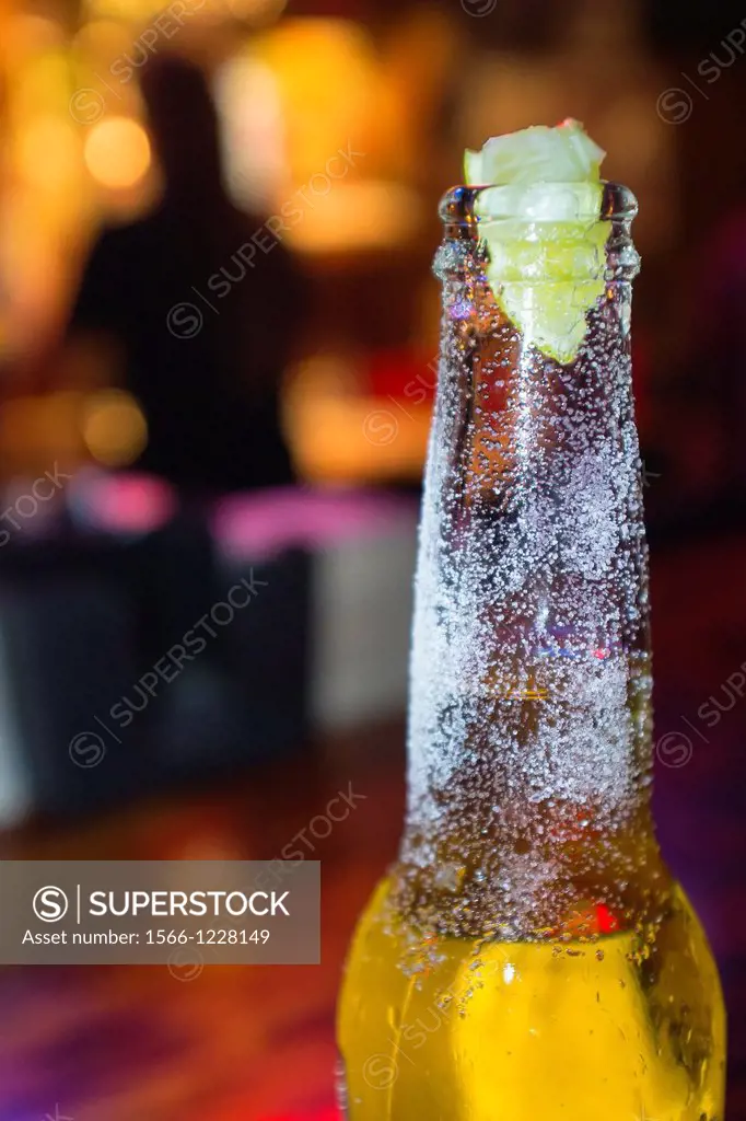 Beer bottle neck dressed with salt and lime on the counter of a bar
