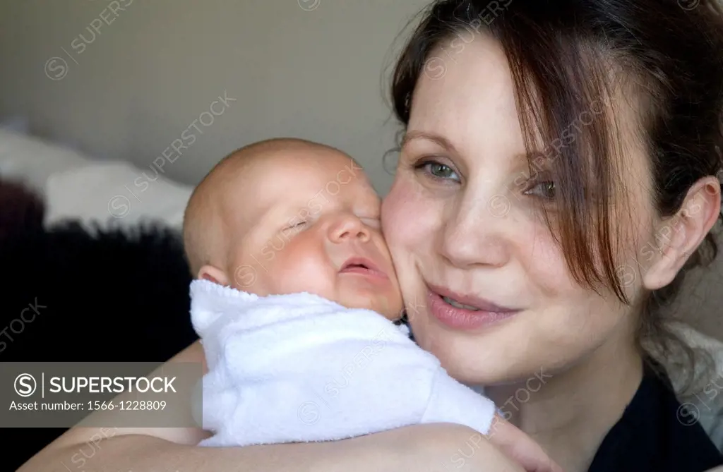 Smiley mother hugging newborn