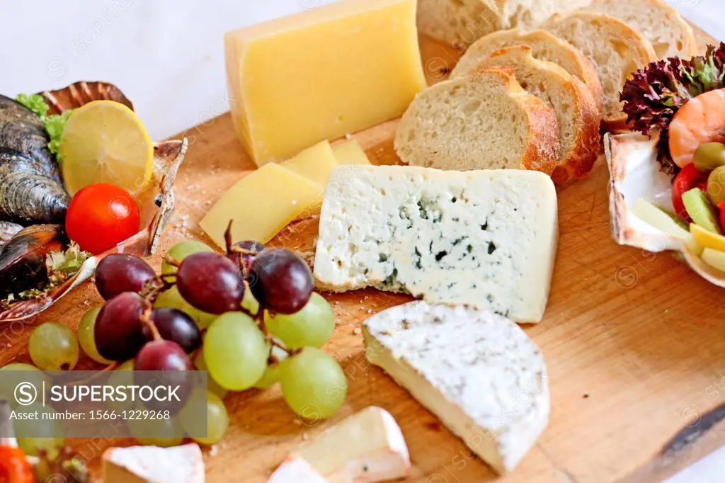Cheese and grapes  Brick cheese, bleu cheese, pepper cheese and Camembert cheese, green and red graps on salad board  Small seafood bits are nested in...