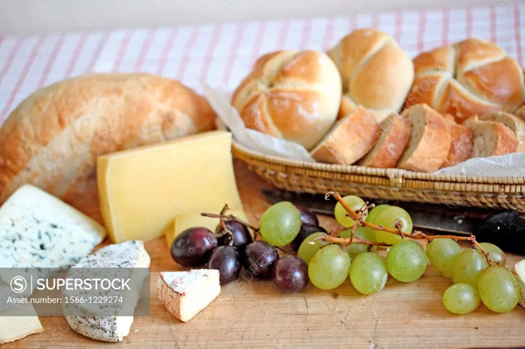 Bread and cheese board  Bleu cheese, paprika cheese, pepper cheese, hard brick cheese, red and green grapes  Basket of bread rolls and sliced soda bre...