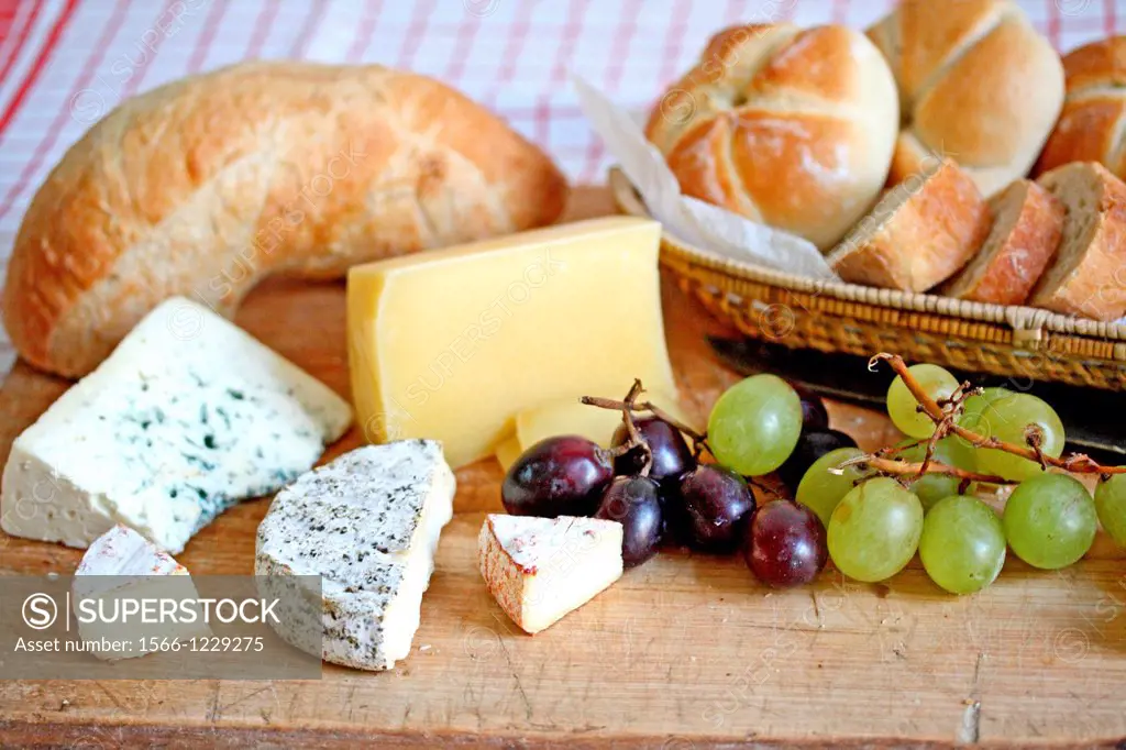 Bread and cheese board  Bleu cheese, paprika cheese, pepper cheese, hard brick cheese, red and green grapes  Basket of bread rolls and sliced soda bre...