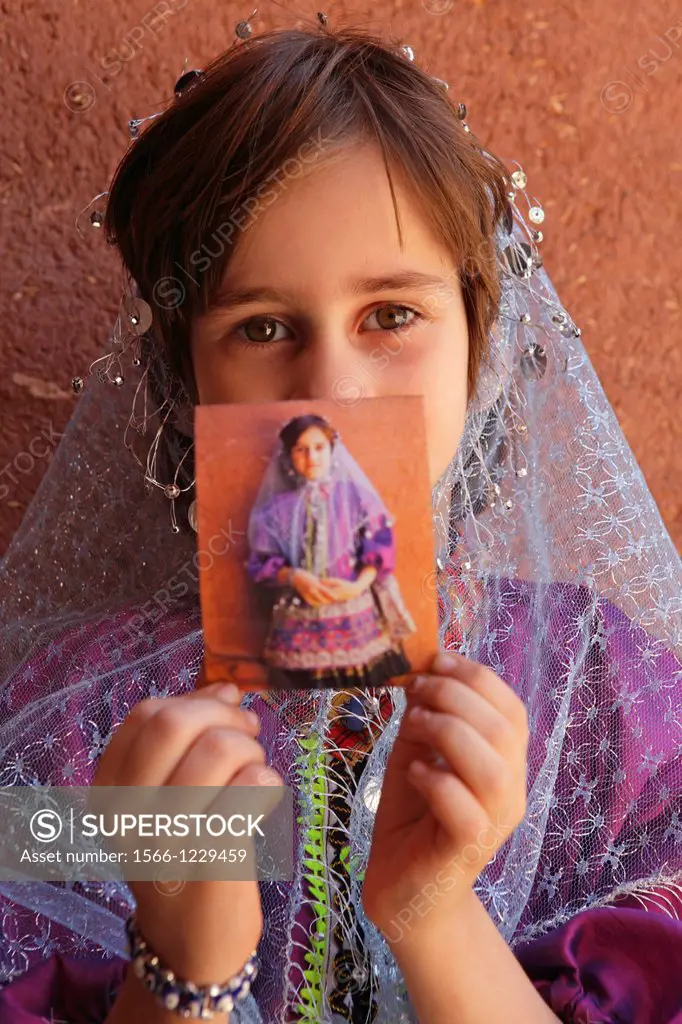 Portrait of a young iranian girl showing a Polaroid, Abyaneh, Iran