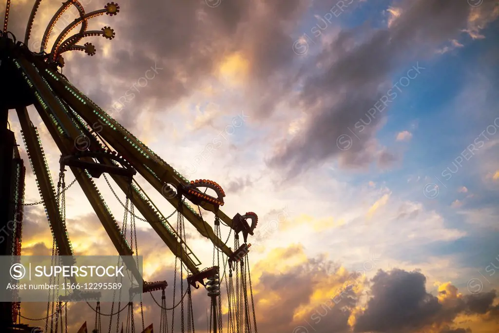 An amusement ride at a county fair stands idle against the sunset.