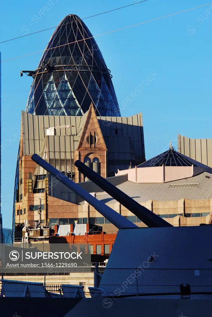 View of the City of London financial district seen from across the River Thames with a gun turret of HMS Belfast in the foreground, on a sunny day in ...