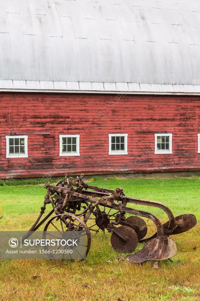 Close up of a red barn and a historic plough in North Randolph, Vermont, USA