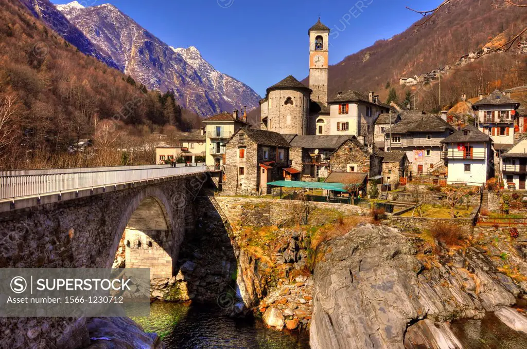 Alpine village with snow-capped mountain and a bridge over a river