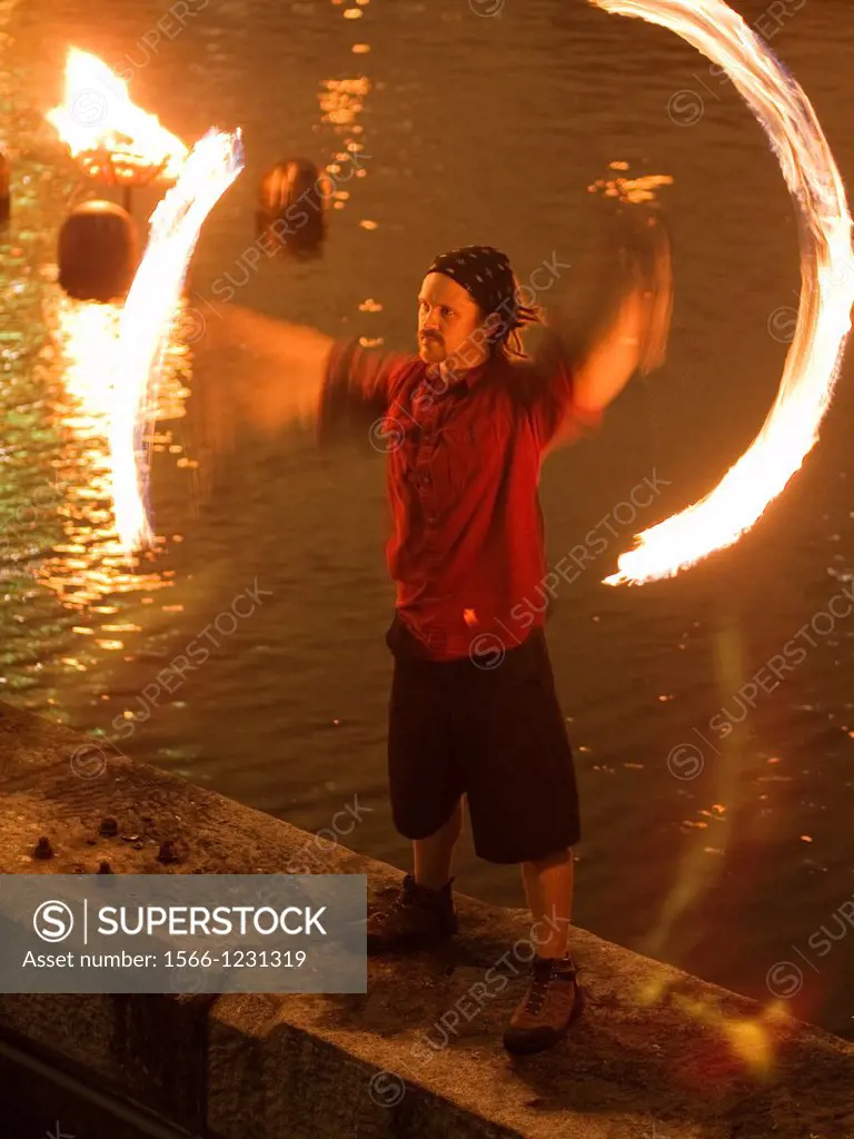 Performer juggling flames in front of river during ´Waterfire´ a performance art event with fires on the river in Providence, Rhode Island, United Sta...