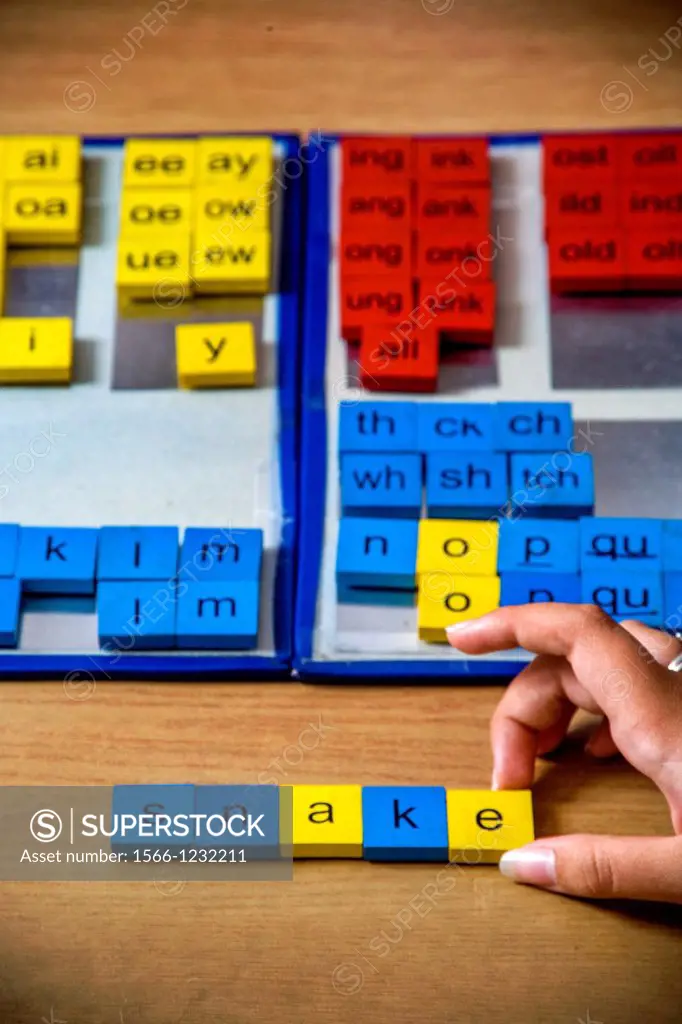 A certified dyslexia testing specialist in a uses colored tile manipulation for a multisensory approach to spelling words for a dyslexic pupil  Vowels...