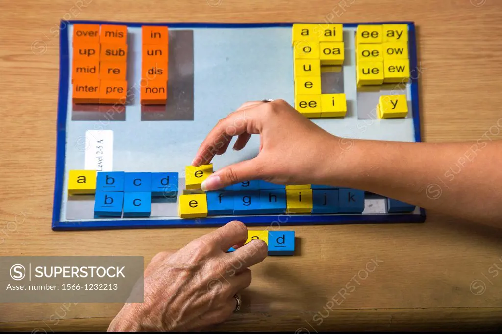 A certified dyslexia testing specialist in a uses colored tile manipulation for a multisensory approach to spelling words for a dyslexic pupil  Vowels...