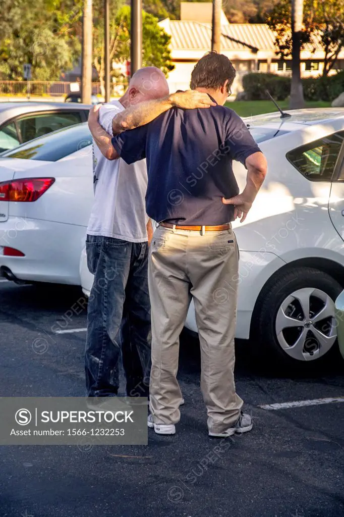 Arm in arm, two men pray together in a Laguna Niguel, CA, parking lot