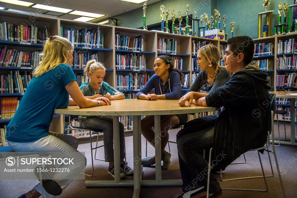 A junior high school counsellor meets with a multiethnic group of students in a San Clemente, CA, school library