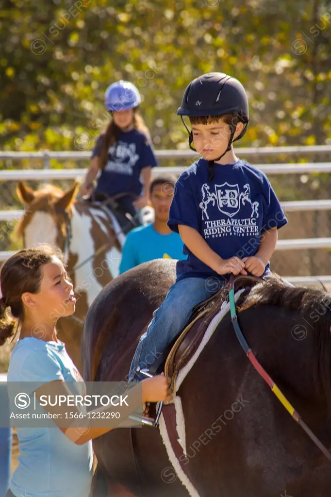 A boy suffering from Van Willebrand Disease and high functioning autism rides a horse as part of therapeutic riding or hipotherapy in Huntington Beach...
